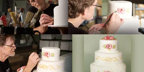 A collage of four photographs showing a baker hand-painting floral designs onto a multi-tiered white wedding cake.