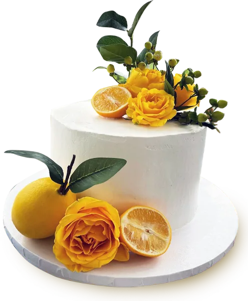 A white frosted cake decorated with yellow roses, green leaves, and fresh citrus fruit.