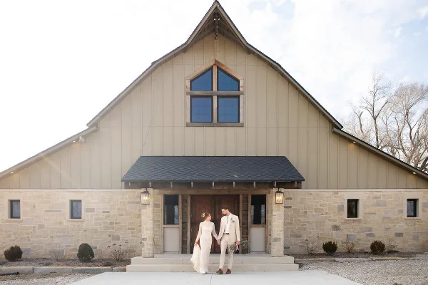 Bride and groom standing together in front of a modern stone and wood wedding venue.