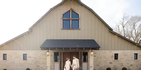 Bride and groom standing together in front of a modern stone and wood wedding venue.