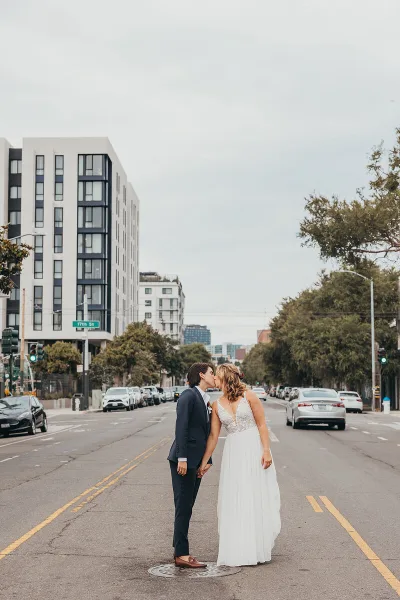 A bride and groom sharing a kiss in the middle of a city street.