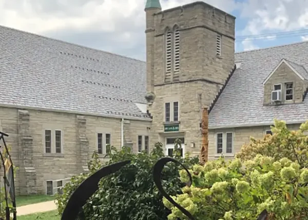 Exterior view of the historic stone building of Art Sanctuary of Indiana with a tower and slate roof.