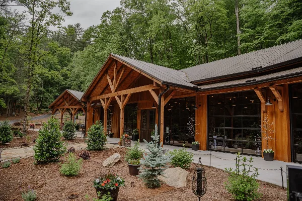 Exterior view of a timber frame wedding venue building surrounded by a forest and landscaped grounds.