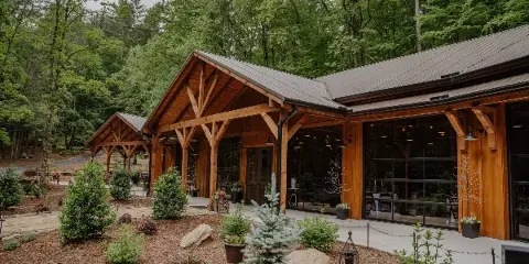 Exterior view of a timber frame wedding venue building surrounded by a forest and landscaped grounds.