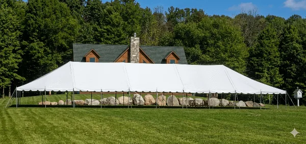 A large white event tent set up on a lawn in front of a house.