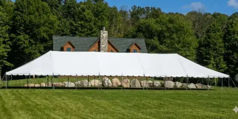 A large white event tent set up on a lawn in front of a house.
