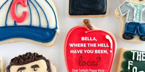 An assortment of intricately decorated iced sugar cookies featuring custom designs and text.