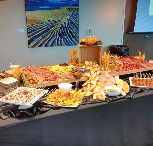 A catering buffet table displaying a charcuterie board, breads, and assorted appetizers.