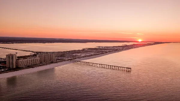 Aerial view of a coastal beach and pier at sunset