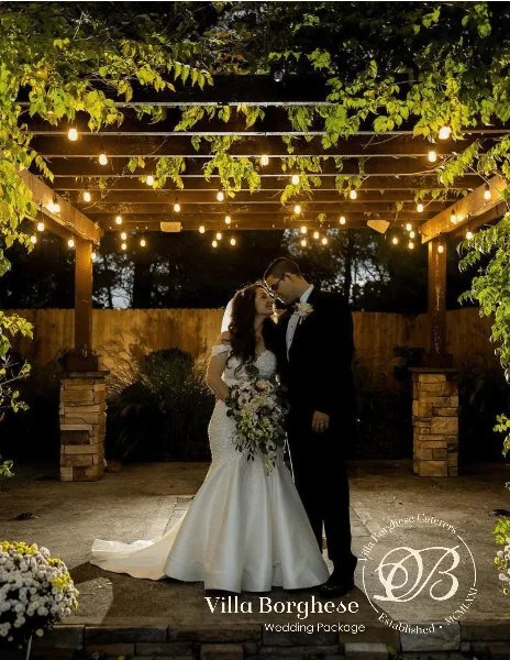 A bride and groom standing under a wooden pergola with string lights, with the Villa Borghese Caterers logo and text overlaid at the bottom.