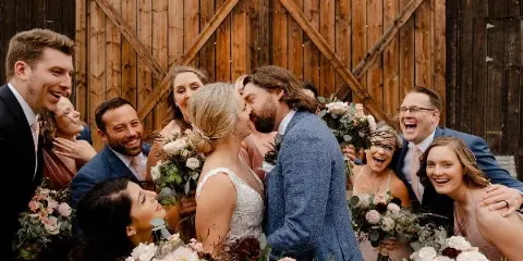 A wedding party posing for a photo in front of a rustic wooden barn door.