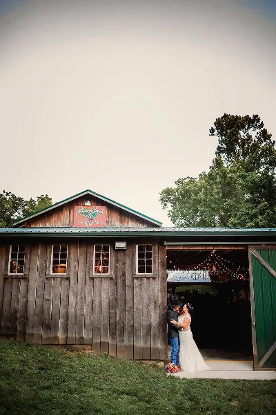 A rustic wooden barn with a 'Black Jack Vineyards' sign on the roof, featuring a bride and groom standing in the open doorway.