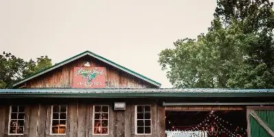 A rustic wooden barn with a 'Black Jack Vineyards' sign on the roof, featuring a bride and groom standing in the open doorway.