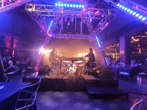 A live band performing on a stage with professional lighting and a drum set during an event.
