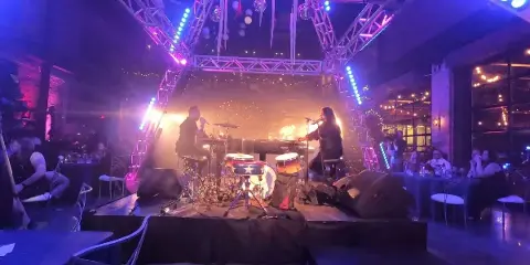 A live band performing on a stage with professional lighting and a drum set during an event.