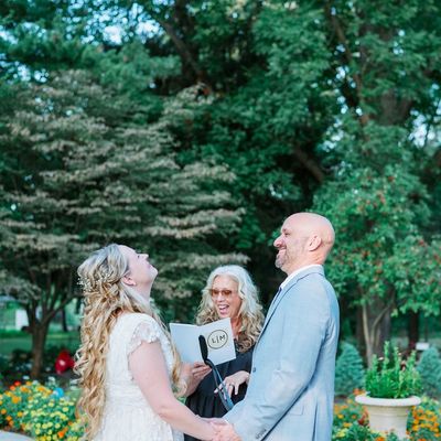 A wedding officiant leading a bride and groom during an outdoor ceremony.