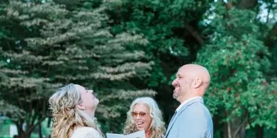 A wedding officiant leading a bride and groom during an outdoor ceremony.
