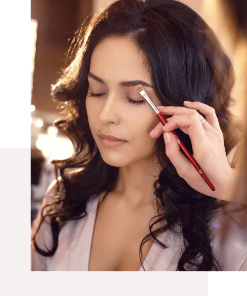 A makeup artist applying makeup to a woman's face with a brush.
