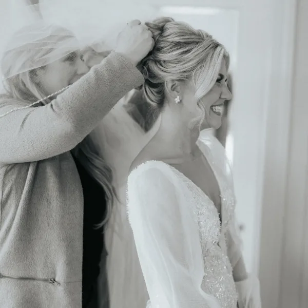 A hair and makeup artist styling a bride's hair in an elegant updo.