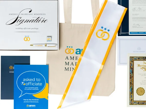 A flat lay of the American Marriage Ministries Signature Wedding Officiant Package, featuring a white and gold stole, an 'Asked to Officiate' workbook, a certificate, and a tote bag.