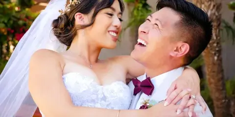 A smiling bride and groom embracing in a close-up wedding portrait.