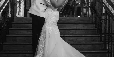 Black and white photograph of a bride and groom embracing on a wooden staircase.