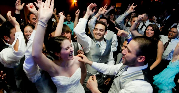 A bride and groom dancing with guests at a wedding reception.