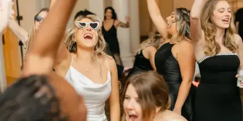 Guests dancing at a wedding reception with raised hands and festive atmosphere.