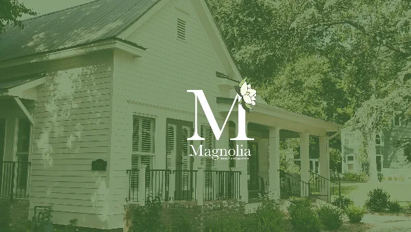 Exterior view of a white historic house with a front porch and surrounding garden, branded as Magnolia House and Garden.