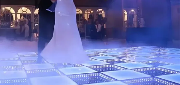 A bride and groom dancing on a glowing blue LED dance floor at a wedding reception.