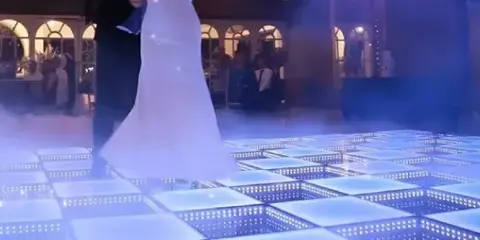 A bride and groom dancing on a glowing blue LED dance floor at a wedding reception.