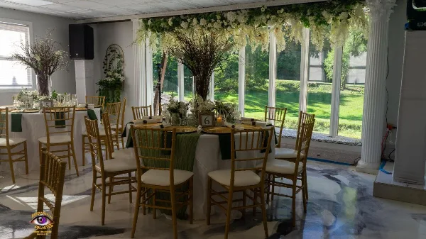 Indoor wedding reception venue with decorated tables, gold chairs, and floral arrangements.