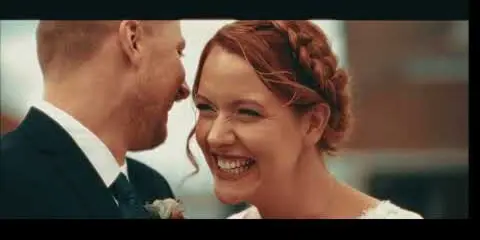 A cinematic close-up of a smiling bride and groom sharing a moment during their wedding.