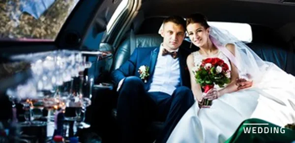 A bride and groom sitting in the back seat of a luxury limousine.