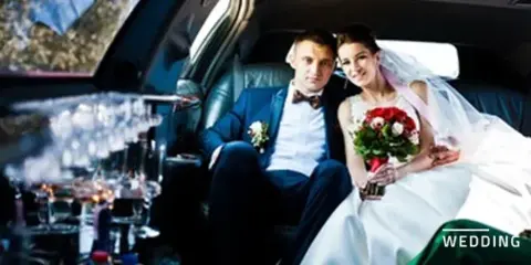 A bride and groom sitting in the back seat of a luxury limousine.