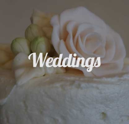 Close-up of a white wedding cake decorated with a large sugar rose and buds.