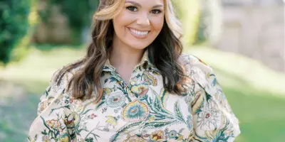 Portrait of a smiling woman holding a professional camera outdoors
