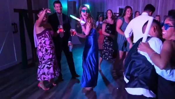 Guests dancing at a wedding reception with colorful lighting and glow sticks.