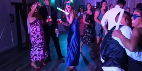 Guests dancing at a wedding reception with colorful lighting and glow sticks.
