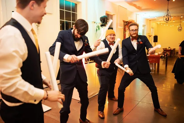 Guests dancing at a wedding reception with a DJ light fixture visible in the background.