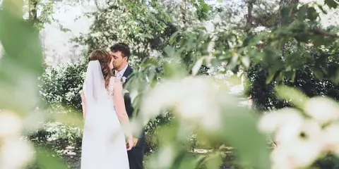 A bride and groom sharing a kiss in an outdoor garden setting.