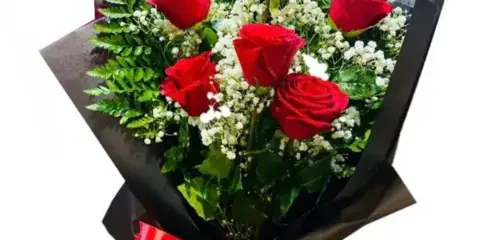 A bouquet of red roses with white filler flowers wrapped in black paper