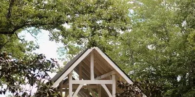 A white timber-frame wedding chapel with a peaked roof, set among trees with a lake visible in the background.