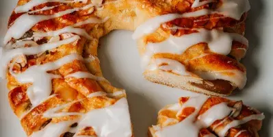 A braided pastry with white icing on a white plate