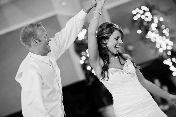 A bride and groom dancing joyfully at a wedding reception.