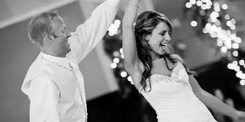A bride and groom dancing joyfully at a wedding reception.