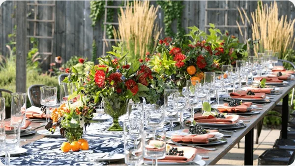 A long event table set with blue and white linens, glassware, and floral centerpieces.