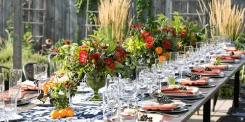 A long event table set with blue and white linens, glassware, and floral centerpieces.
