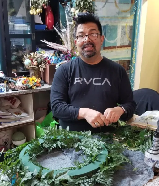 A florist working on a greenery wreath in a flower shop