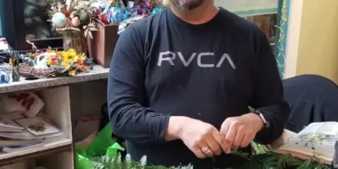A florist working on a greenery wreath in a flower shop